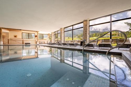 a house with a pool with chairs and windows at Monte Pana Dolomites Hotel in Santa Cristina Gherdëina