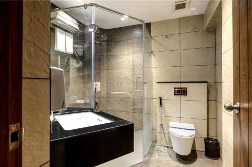 La salle de bains est pourvue d'un lavabo, de toilettes et d'une douche. dans l'établissement Sundex Hotel, à Thanjavur