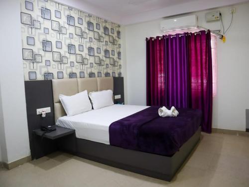 a bedroom with a bed with purple sheets and a window at Libra Cottage in Port Blair