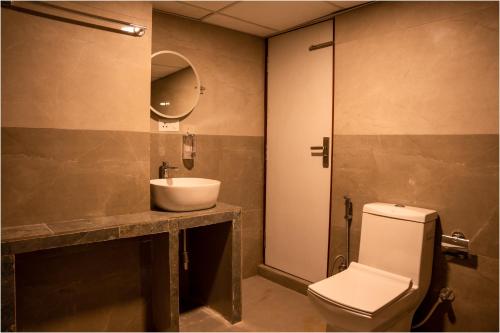 W łazience znajduje się umywalka, toaleta i lustro. w obiekcie Nag Pukhu Guest House w mieście Bhaktapur