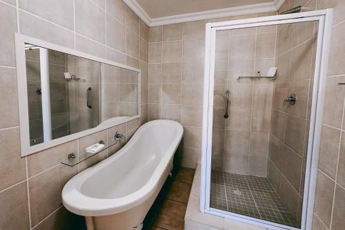 a bathroom with a shower and a tub and a sink at Assegaaibosch Country Lodge in Kareedouw