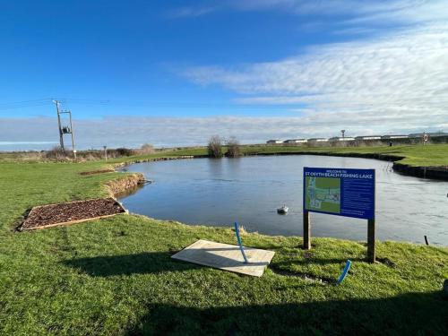 a sign in the grass next to a body of water at Luxurious Three Bedroom Caravan in Jaywick Sands