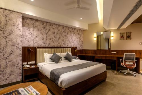 - une chambre avec un lit, un bureau et une chaise dans l'établissement Sundex Hotel, à Thanjavur