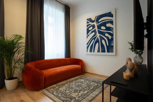 una sala de estar con una silla naranja y una ventana en 2-rooms apartment 10 min away from city center, en Viena