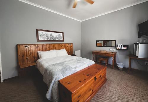 een slaapkamer met een bed met een houten hoofdeinde bij Assegaaibosch Country Lodge in Kareedouw