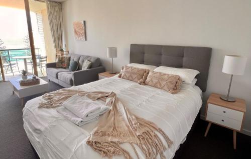 a bedroom with a large bed and a couch at Top Floor Beachside Apartment in the Heart of Mooloolaba in Mooloolaba