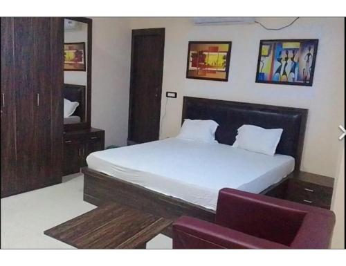 a bedroom with a bed and a purple chair at Hotel Saraswati International, Muzaffarapur in Muzaffarpur