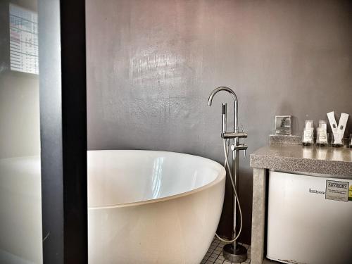 a white bath tub in a bathroom with a counter at Rest Chinatown Hotel in Singapore