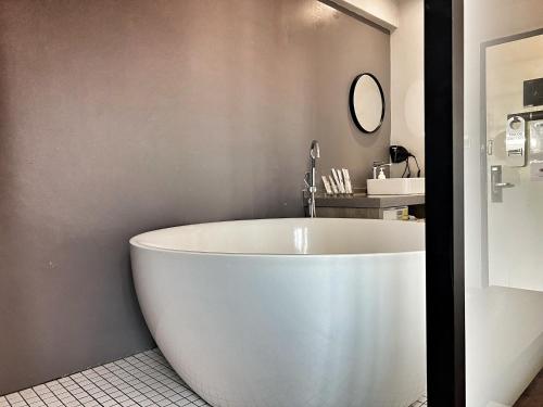 a white bath tub in a bathroom with a sink at Rest Chinatown Hotel in Singapore
