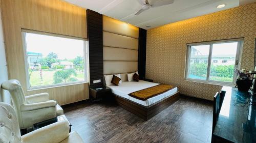 a bedroom with a bed and a chair and two windows at Hotel Riya Palace By Standards in Haldwāni