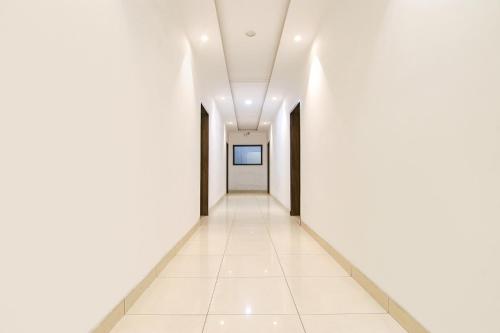 un pasillo vacío en un edificio de oficinas con paredes blancas y suelos blancos en FabHotel Ace en Ludhiana
