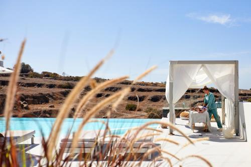 a man standing under a white tent next to a pool at Adorno Oia in Oia