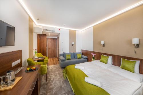 a bedroom with a large bed and a living room at Szarvaskút Hotel in Zirc