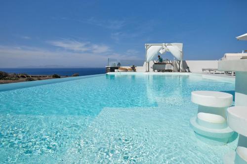 a large swimming pool with blue water and the ocean at Adorno Oia in Oia