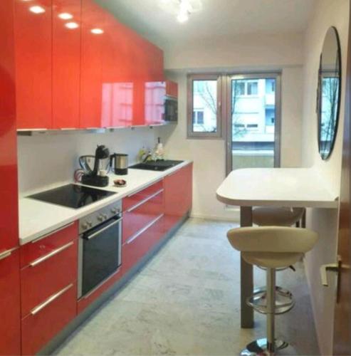 uma cozinha com armários vermelhos e um balcão branco em City Center Cosy Three Beds em Luxemburgo