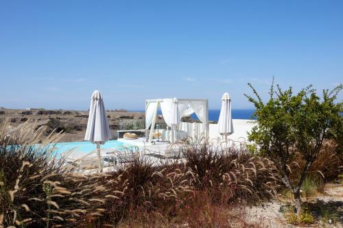 a pool with umbrellas and the ocean in the background at Adorno Oia in Oia