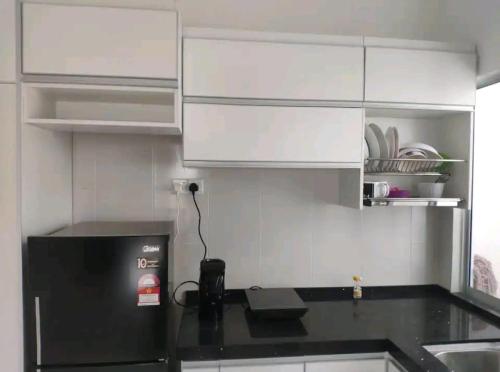 a kitchen with white cabinets and a black refrigerator at 3 Bedroom Apartment with Pool and Beautiful View in Klebang, Ipoh in Chemor