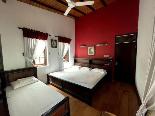 duas camas num quarto com paredes vermelhas em Luxury Fully furnished house for 8 people ! em Sri Jayewardenepur- Kotte