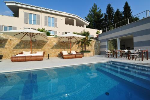 ein Pool mit zwei Sonnenschirmen und ein Haus in der Unterkunft Zeno Suites in San Zeno di Montagna