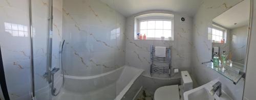 baño blanco con ducha y lavamanos en Luxury Apartment Limehouse en Londres