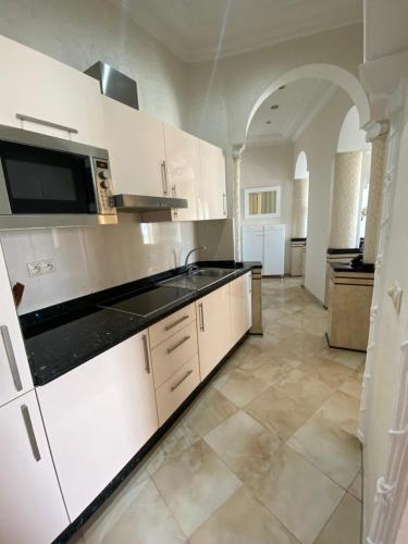 een keuken met witte kasten en een zwart aanrechtblad bij Appartement Playa de Tanger/ Marina Bay in Tanger