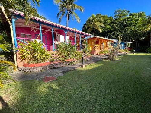 a pink house with a lawn in front of it at Le Nid Tropical in Bouillante