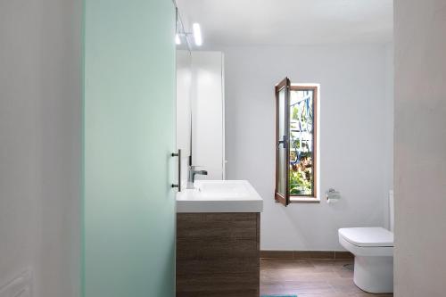 een badkamer met een wastafel, een toilet en een spiegel bij Casa Garten in Tijarafe