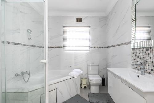 La salle de bains blanche est pourvue d'une baignoire, de toilettes et d'un lavabo. dans l'établissement Signature Lodge, à Kempton Park