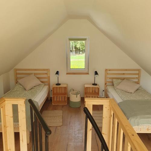 um quarto no sótão com 2 camas e uma janela em Bujanie w sitowiu em Wyszowate