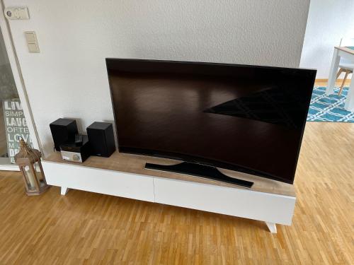 ein großer Flachbildfernseher auf einem weißen Entertainment-Center in der Unterkunft Ferienwohnung Stadtgracht in Nordhorn
