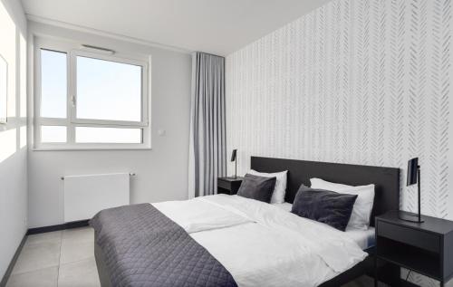 a white bedroom with a bed and a window at Poznań Apartments Towarowa in Poznań