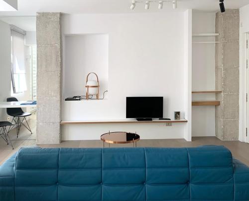 un sofá azul en la sala de estar con TV en Estudio, en Ponferrada