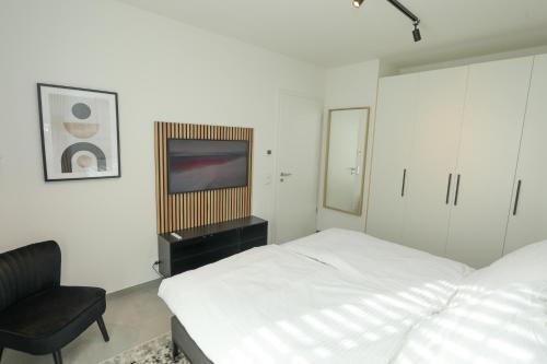 Un dormitorio con una cama y una silla y un televisor. en TimeTidy III, en Hochheim am Main