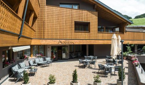 a building with a patio with chairs and umbrellas at Hotel Alpenroyal in Castelrotto