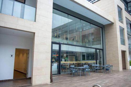 a large glass building with tables and chairs at Sunshine Large 1Bed + Big Balcony @Embassy Gardens in Cantonments