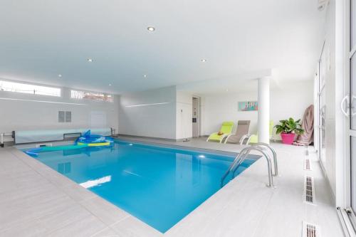 uma grande piscina com água azul num quarto em Villa Enora Bretagne Piscine Intérieure Partagée Jacuzzi privatif 100m Plage em Sibiril