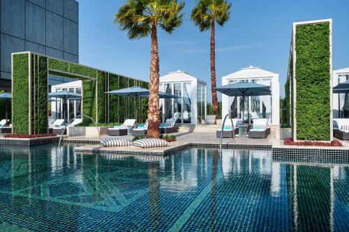 una piscina con palmeras y sombrillas en Waldorf Astoria Kuwait en Kuwait