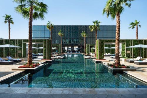 une piscine avec des palmiers en face d'un bâtiment dans l'établissement Waldorf Astoria Kuwait, à Koweït