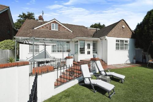a white house with a patio with two chairs at 4 Bedroom Home In Brighton With Hot Tub in Brighton & Hove