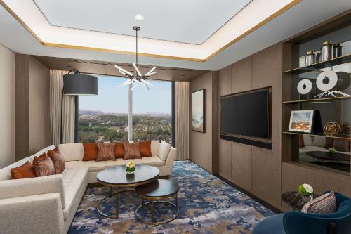 a living room with a couch and a tv at Waldorf Astoria Kuwait in Kuwait