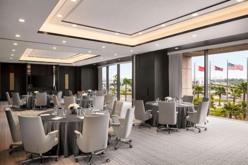 a conference room with tables and white chairs and windows at Waldorf Astoria Kuwait in Kuwait