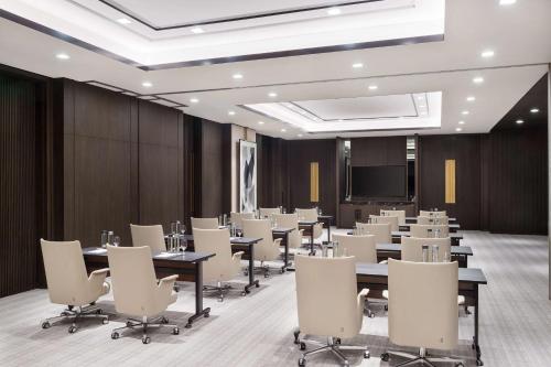 a conference room with tables and chairs and a projection screen at Waldorf Astoria Kuwait in Kuwait