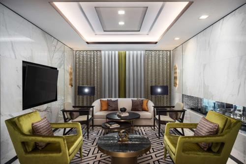 a living room with a couch and chairs and a tv at Waldorf Astoria Kuwait in Kuwait
