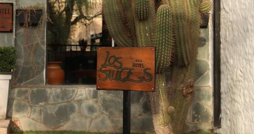 a sign with graffiti on it next to a cactus at Hotel Los Sauces in Cafayate