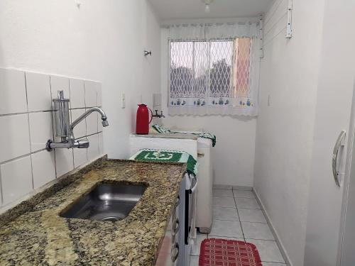 Elle comprend une petite cuisine avec un évier et une fenêtre. dans l'établissement Wi-fi 2 Quartos Portaria 24hs com Garagem, à Itanhaém