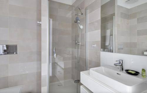 a white bathroom with a sink and a shower at Poznań Apartments Towarowa in Poznań