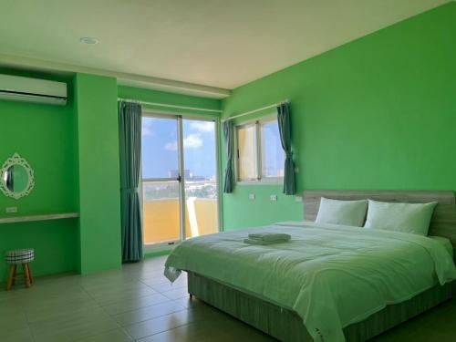 馬公市的住宿－情人灣二館，绿色卧室设有床和大窗户