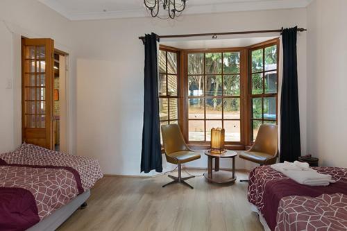 a bedroom with two beds and a table and a window at Juliana's Cottage 4 Bedroom Katoomba Home in Katoomba