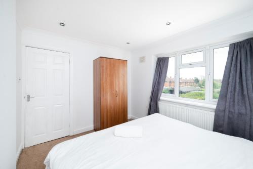 a white bedroom with a bed and a window at 3BR Home A Cosy Ealing Haven in London in Northolt
