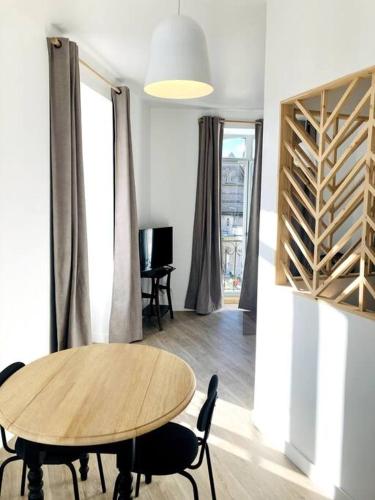 une salle à manger avec une table et des chaises en bois dans l'établissement La Belle Consigne - Appartements Dinan Centre Gare, à Dinan